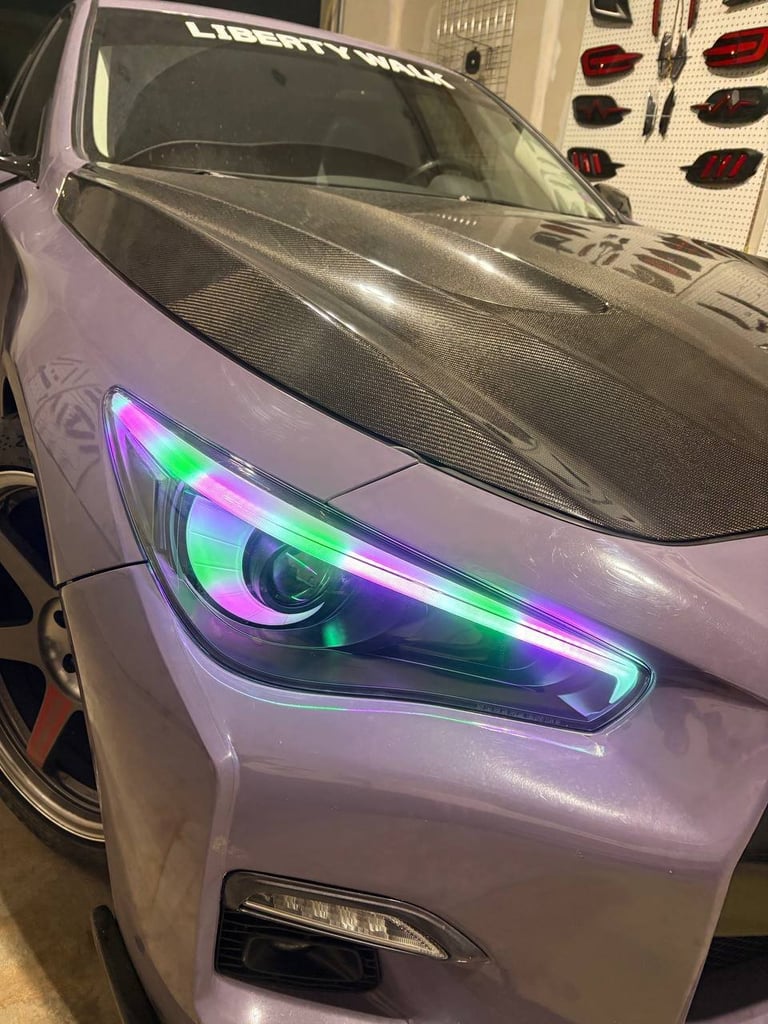 Purple car with custom RGB LED headlights glowing in green and pink colors in a garage workshop